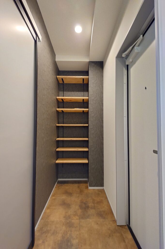 20260615_095014473 | 津山で注文住宅・デザイン住宅をちょうどいい価格で建てる工務店 |住宅産業センター Narrow indoor stairwell with light wood floating steps against a dark textured wall, leading upward in a small hallway.